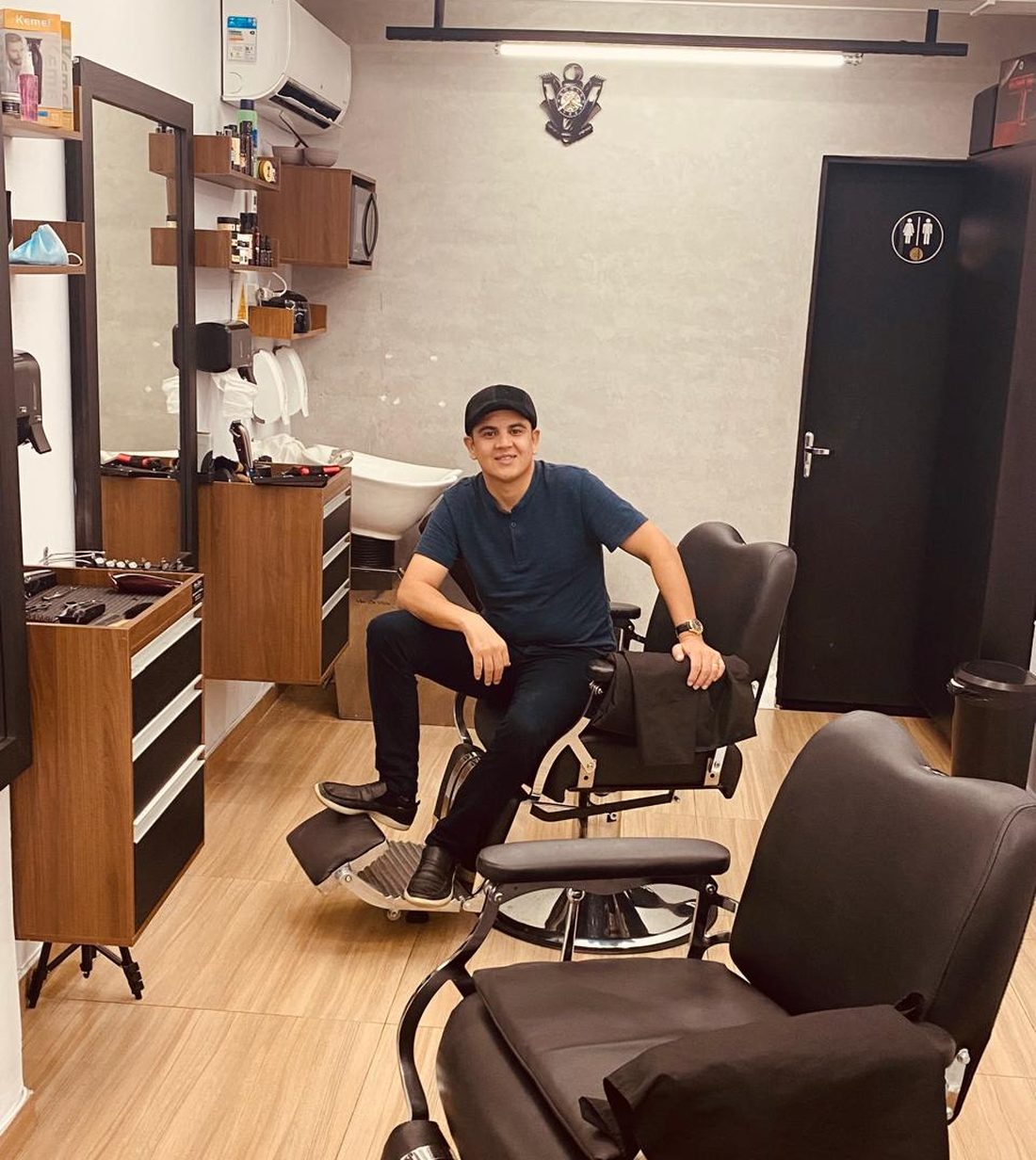 Thiago, o Mineiro, sentado na cadeira de barbeiro do salão da Mineiro Barbearia em Itupeva