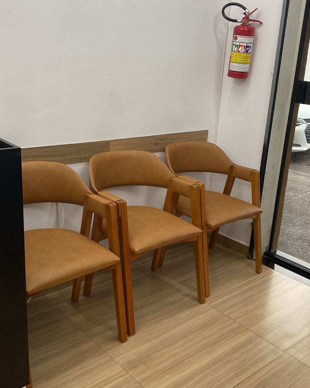 Recepção da Mineiro Barbearia com poltronas de madeira e estofado caramelo
