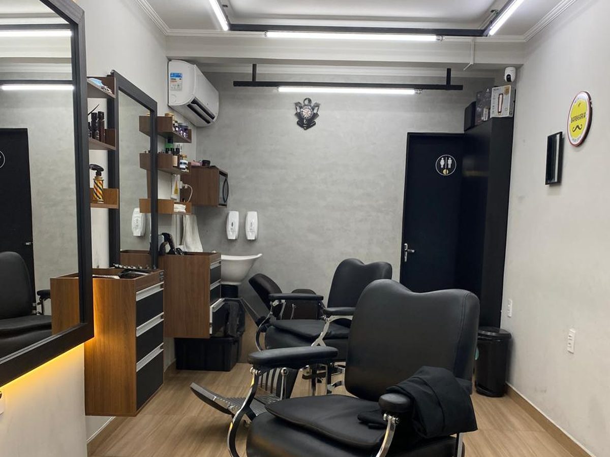 Salão da Mineiro Barbearia com cadeiras de barbeiro, espelhos iluminados e piso de madeira clara